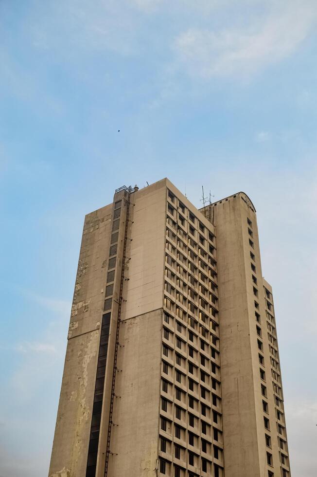 an old skyscraper or apartment that looks dull against a blue sky background photo