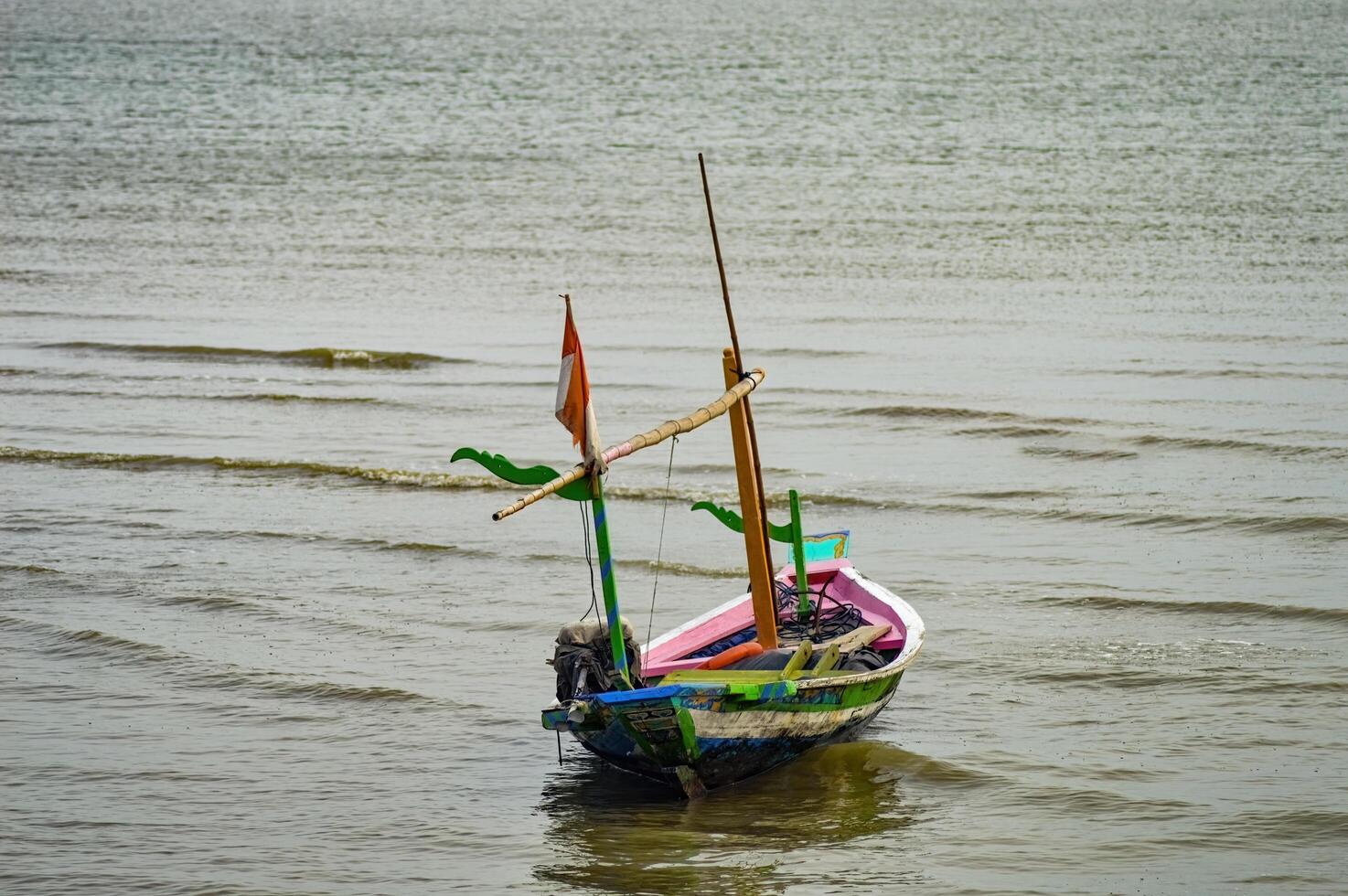 a wooden fishing boat with a small Indonesian flag on it photo