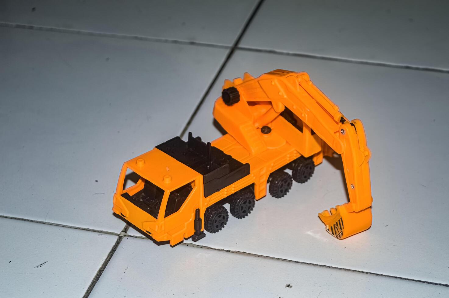 a yellow toy miniature excavator on the floor photo