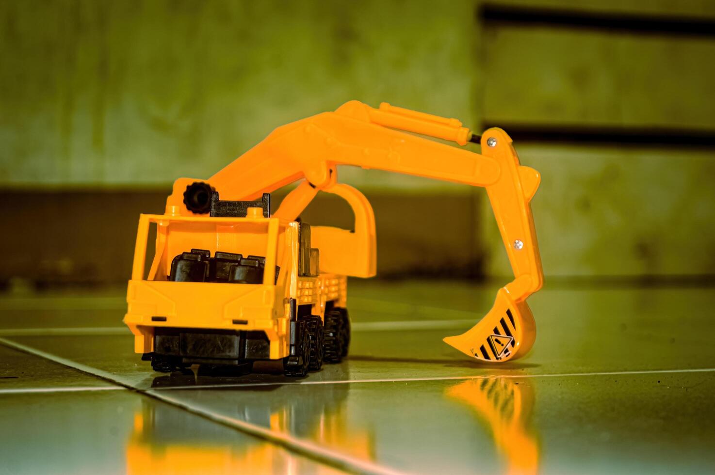 a yellow toy miniature excavator on the floor photo