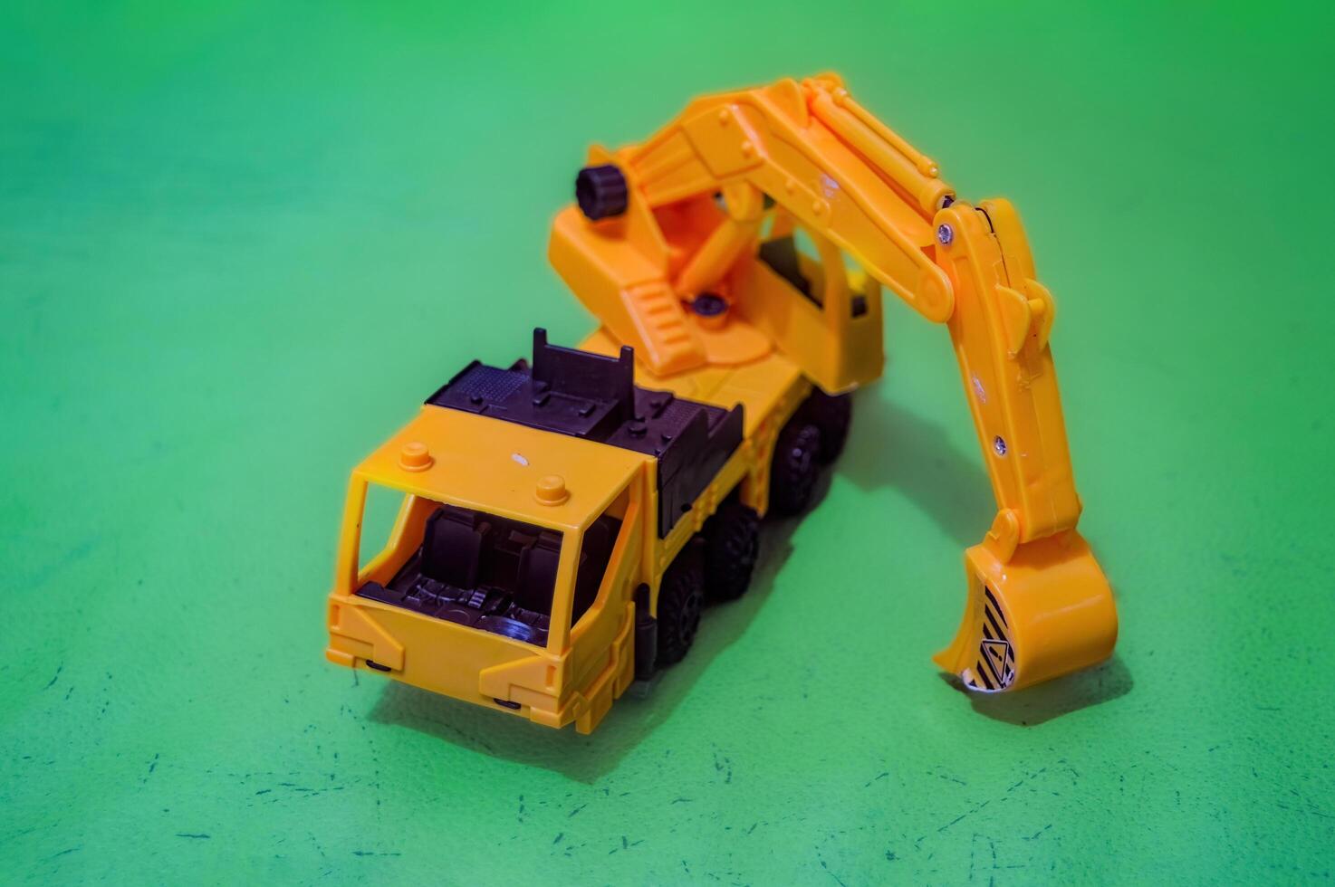 a yellow toy miniature excavator on a flat green background photo