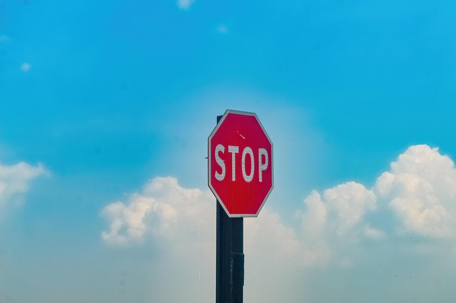 a traffic stop sign with a cloudy blue sky in the background photo