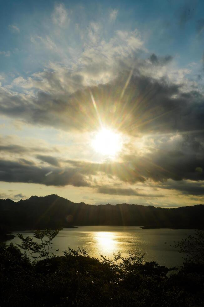 landscape of a lake surrounded by mountains with a cloudy evening sky photo