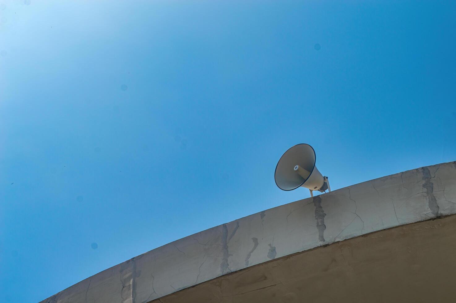 vintage horn speaker mounted on the roof with bright blue sky background photo