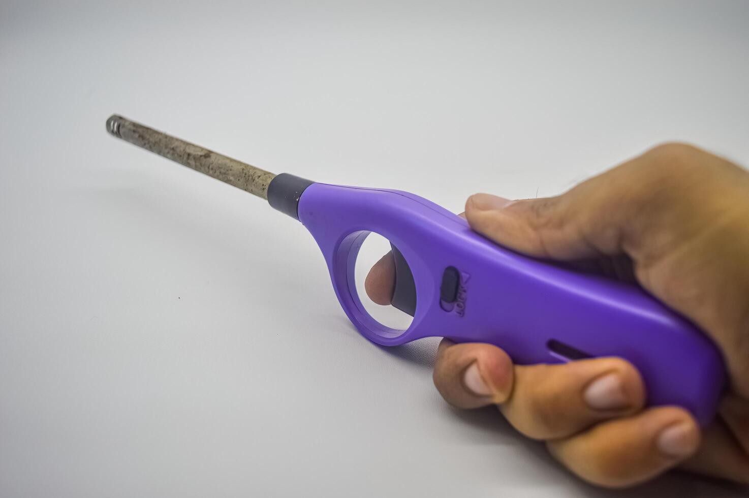 hand holding a purple gas lighter isolated on a white background photo