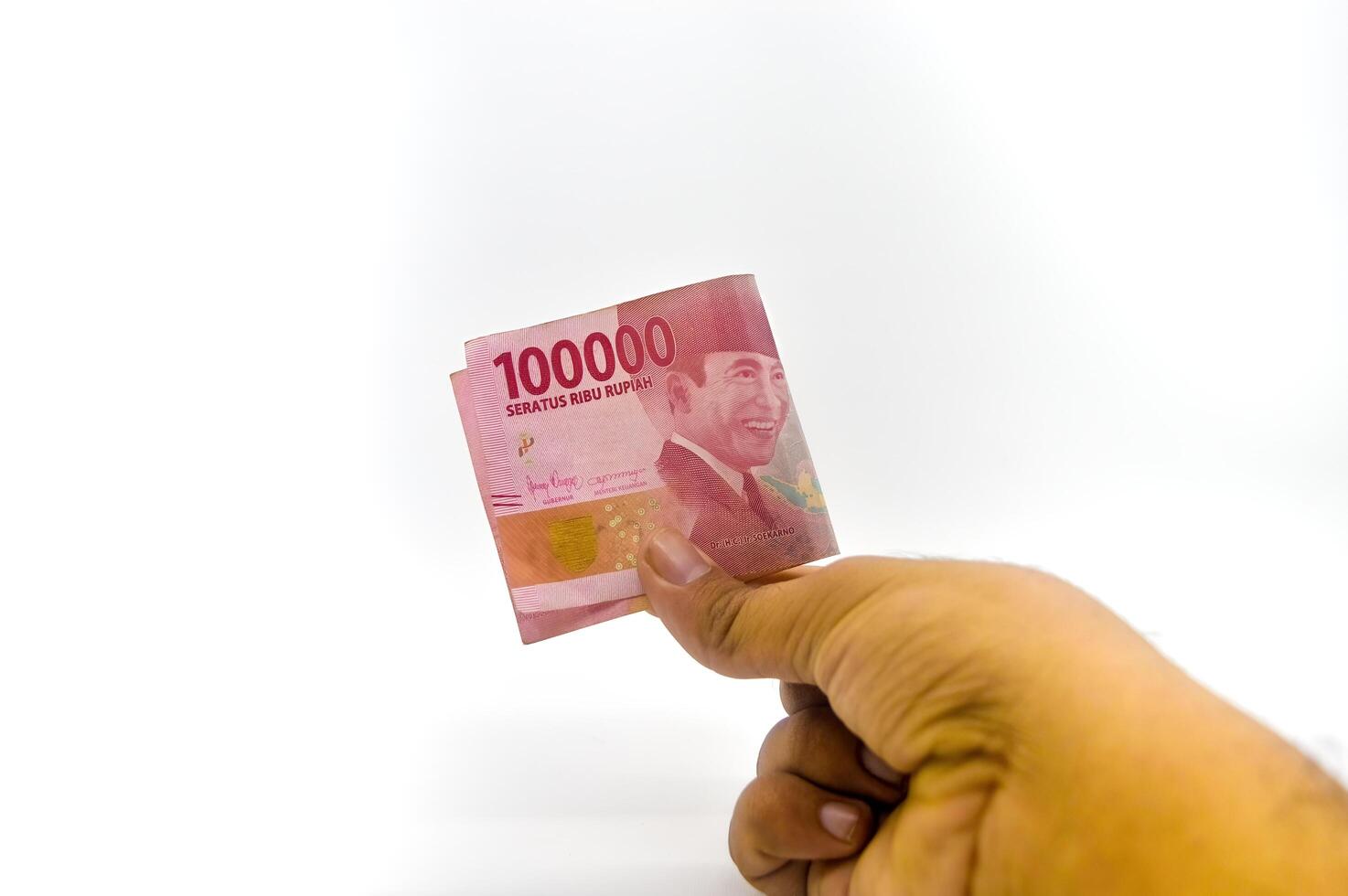 hand holding one hundred thousand rupiah notes isolated on white background photo