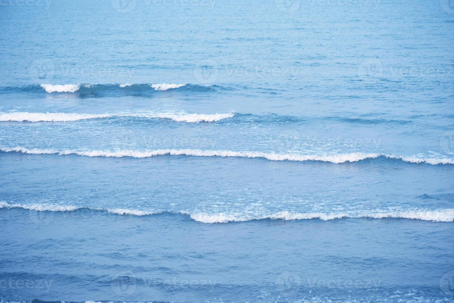 Bluewater waves on the surface ripples blurred. Defocus blurred transparent blue colored clear calm water surface texture with splash and bubbles. Water waves with shining pattern texture background. photo