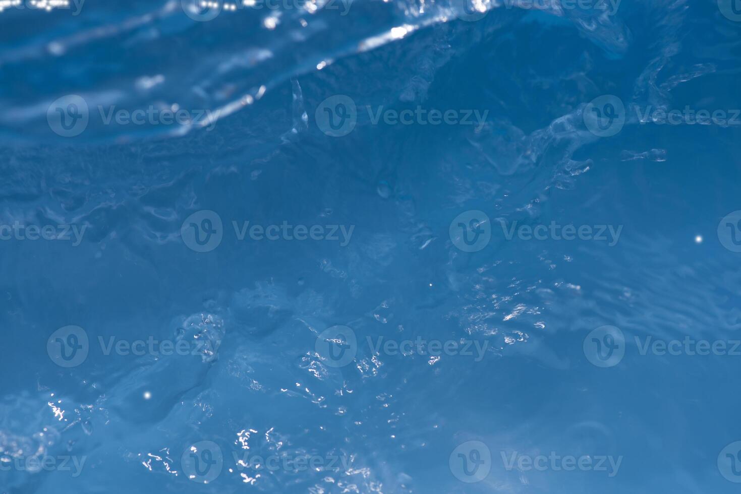 Bluewater waves on the surface ripples blurred. Defocus blurred transparent blue colored clear calm water surface texture with splash and bubbles. Water waves with shining pattern texture background. photo