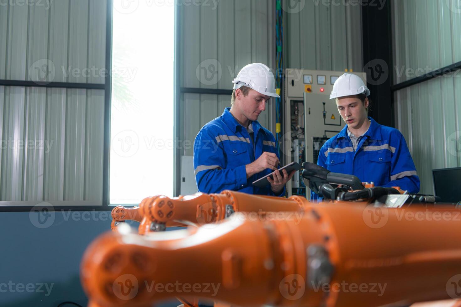 Engineer and technician working with robot arm in factory. Industry and engineering concept. photo