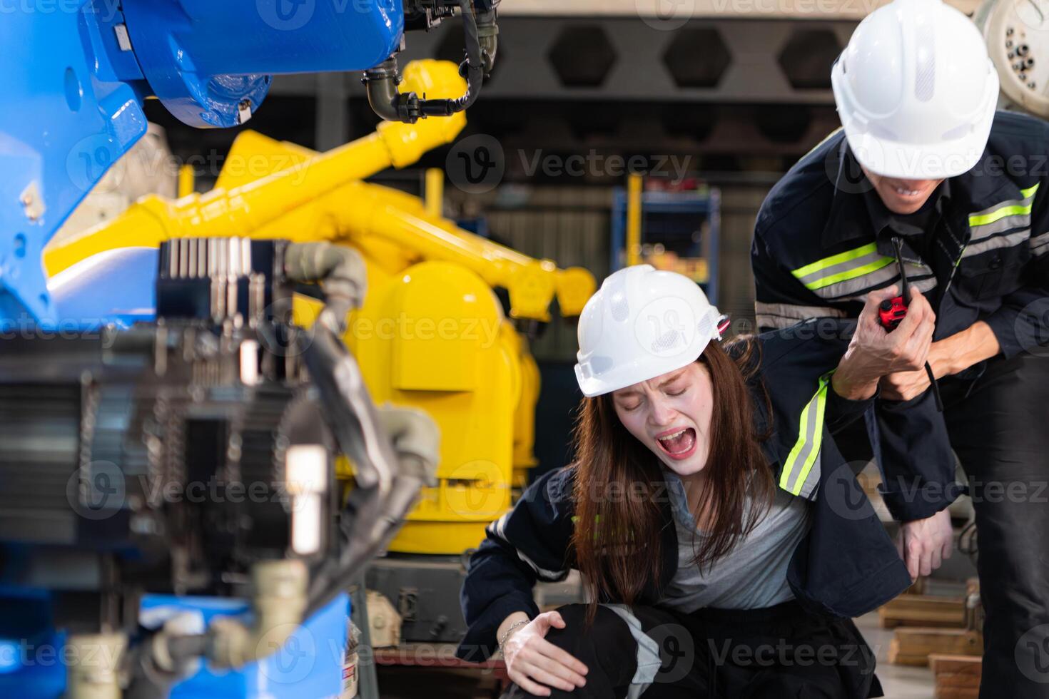 A female worker suffered a leg accident while working in robotic arms factory and male technician is helping and providing first aid. photo