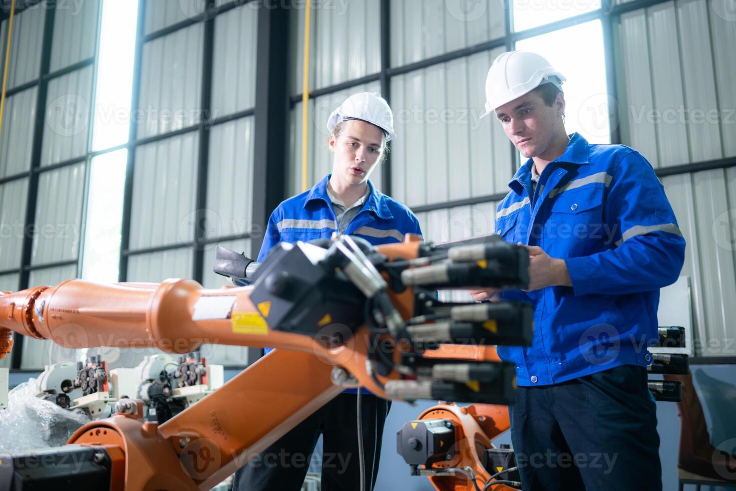 Engineer and technician working with robot arm in factory. Industry and engineering concept. photo