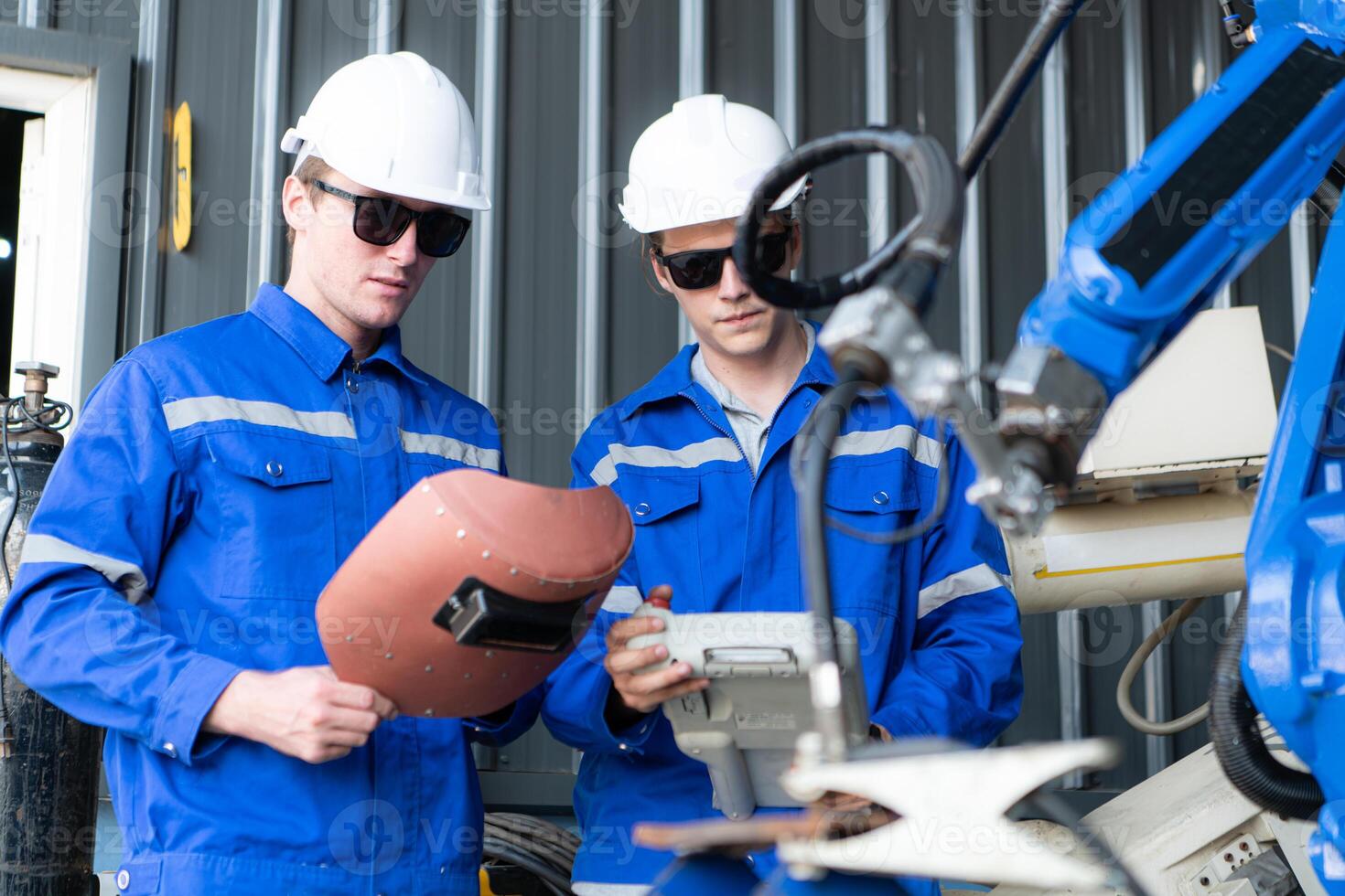 Industrial workers working with robotic arm welding machine in factory, Robotic arm welding industry and engineering concept. photo