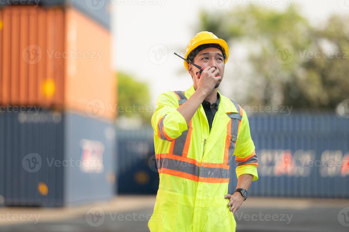 Workers in the import and export industry use walkie talkies to communicate with drivers of reach stacker containers in an empty container warehouse. photo