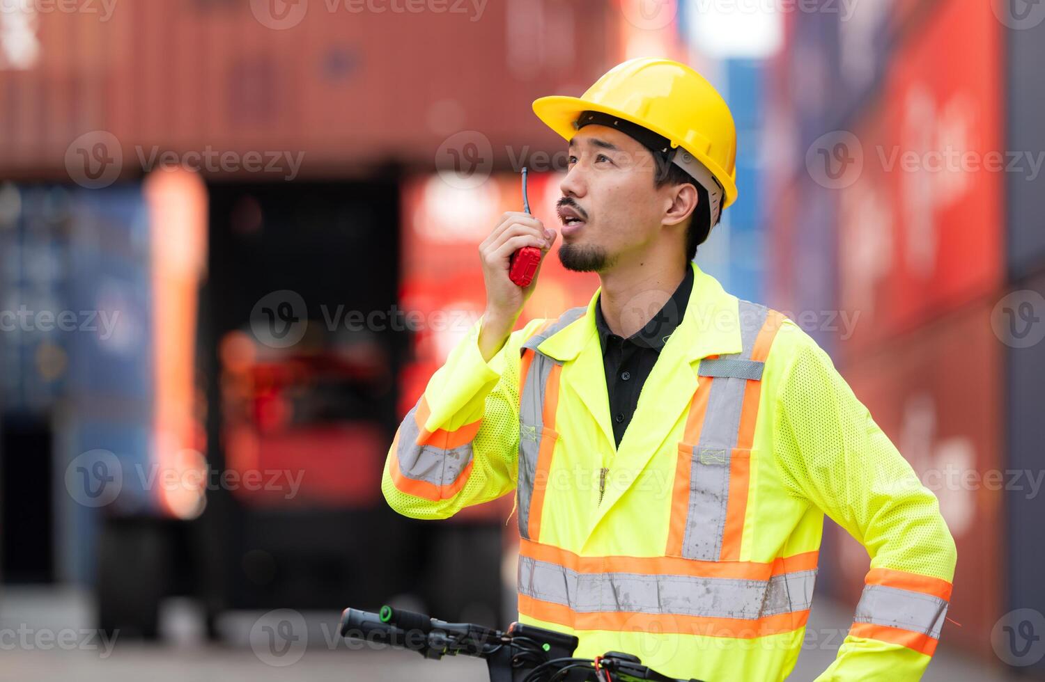 Portrait of a warehouse worker speaking on a walkie talkie with a coworker in an empty container warehouse while driving a scooter to inspect work photo
