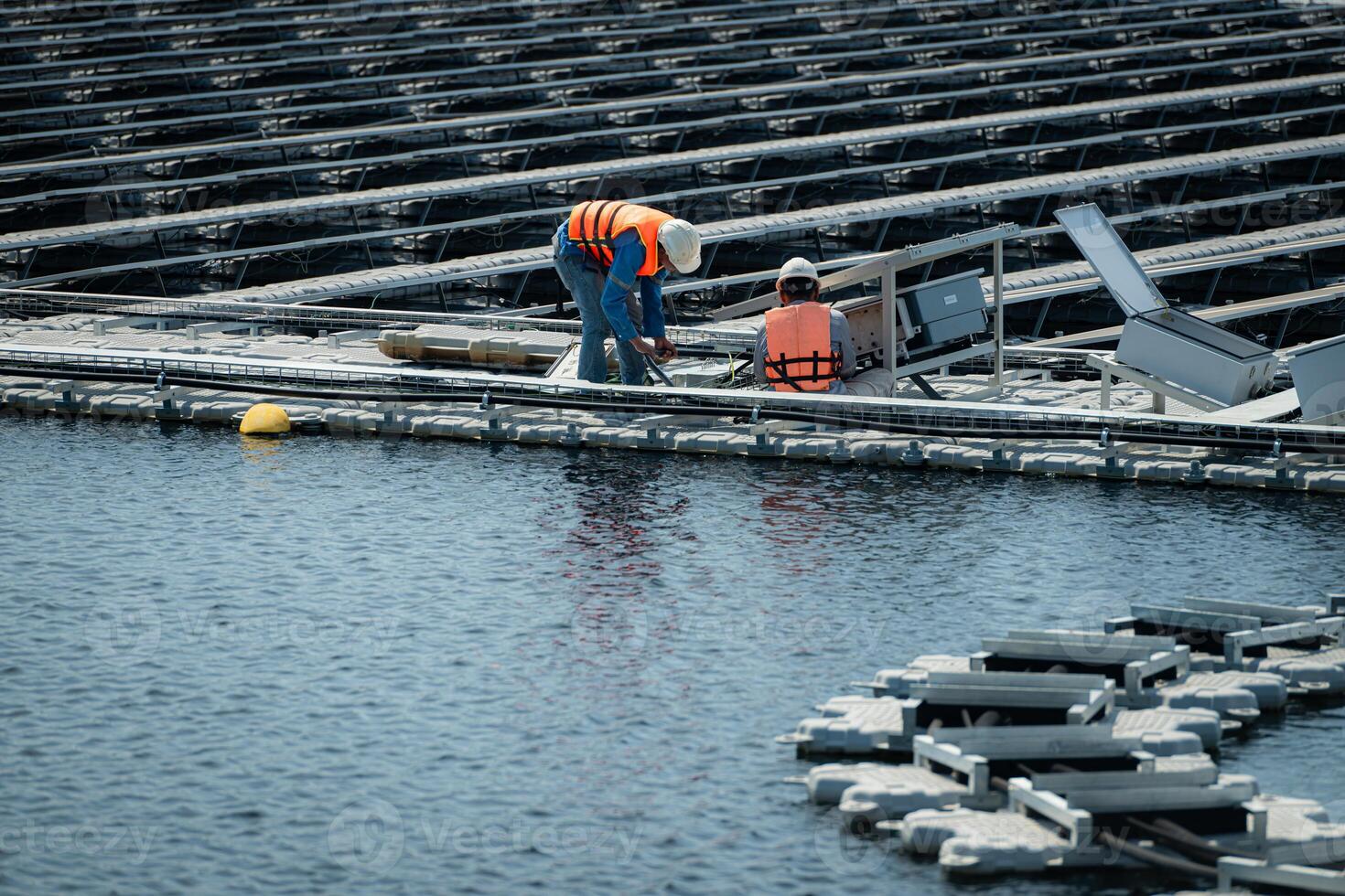 Both of technicians are currently evaluating and repairing the transmission terminals for electricity generated by solar energy in a floating solar power system. photo