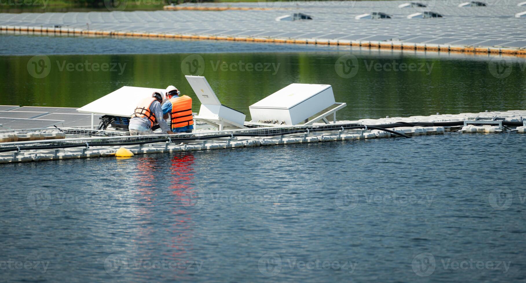 Both of technicians are currently evaluating and repairing the transmission terminals for electricity generated by solar energy in a floating solar power system. photo