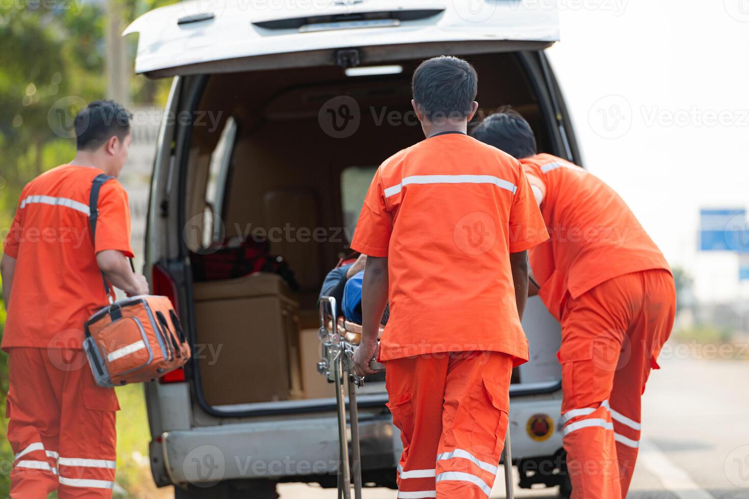 The paramedic  is assisting an injured man in an emergency situation on the road. photo