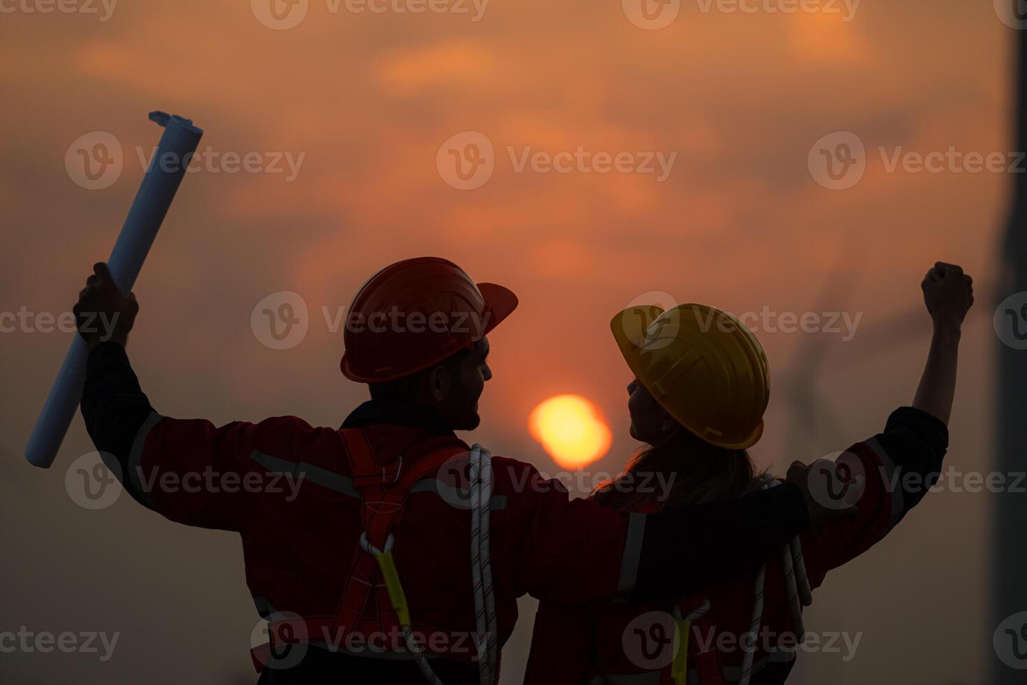 Silhouette of engineer and technician with a wind farm and sunset background photo