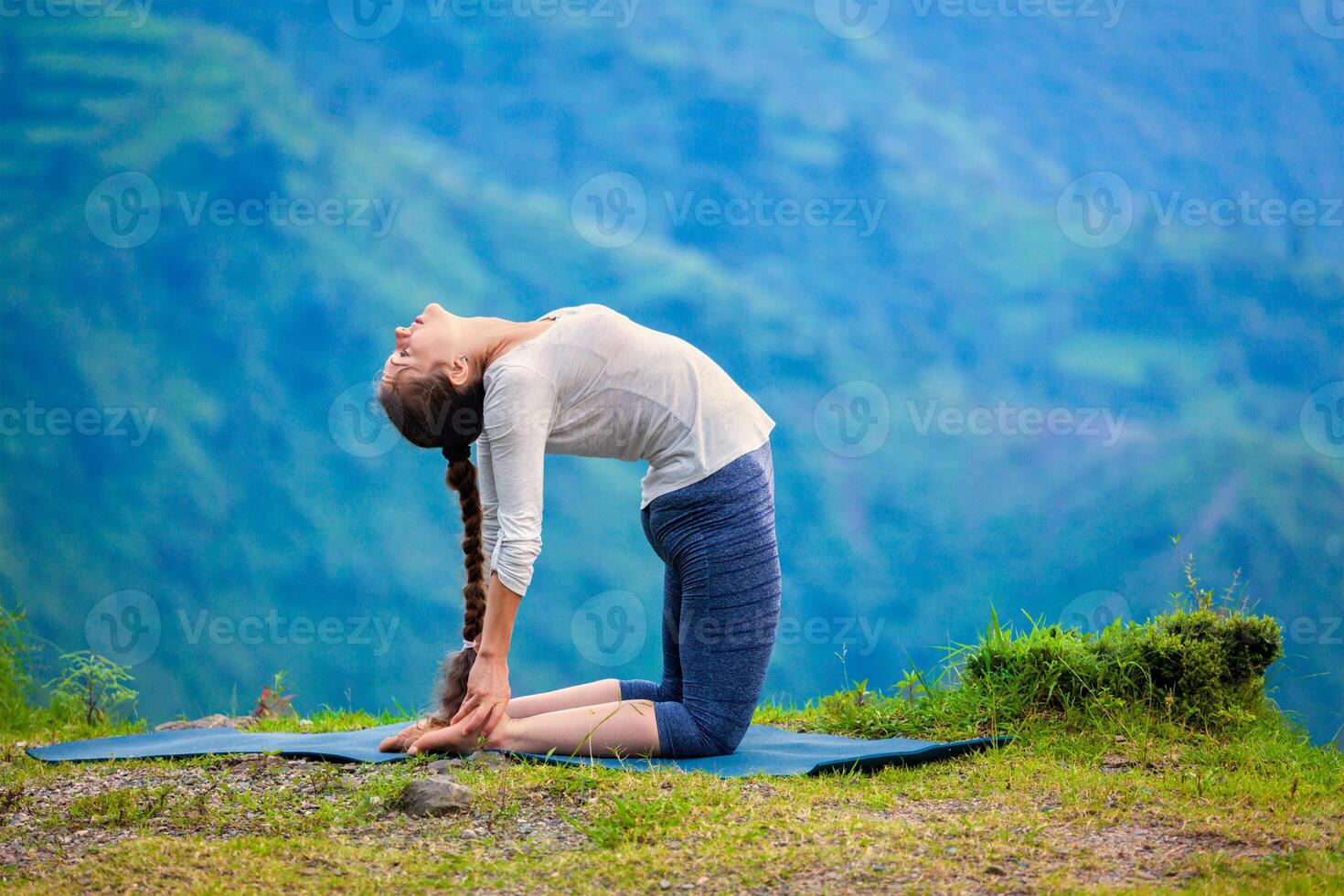 Woman doing yoga asana Ustrasana camel pose outdoors photo