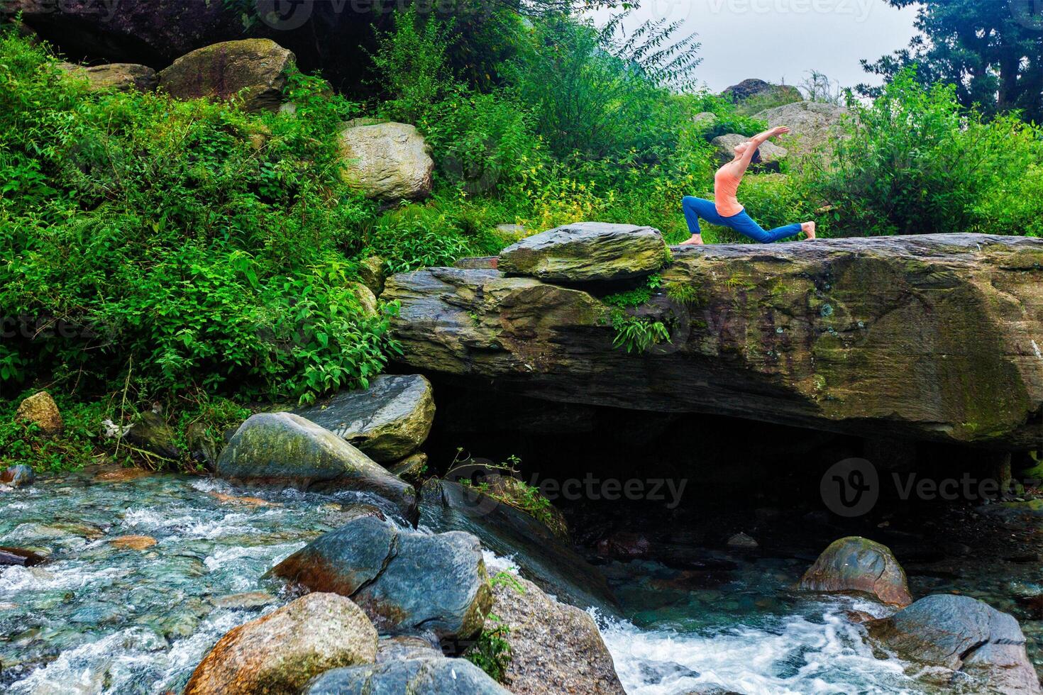 Sporty fit woman practices yoga Anjaneyasana in mountains photo