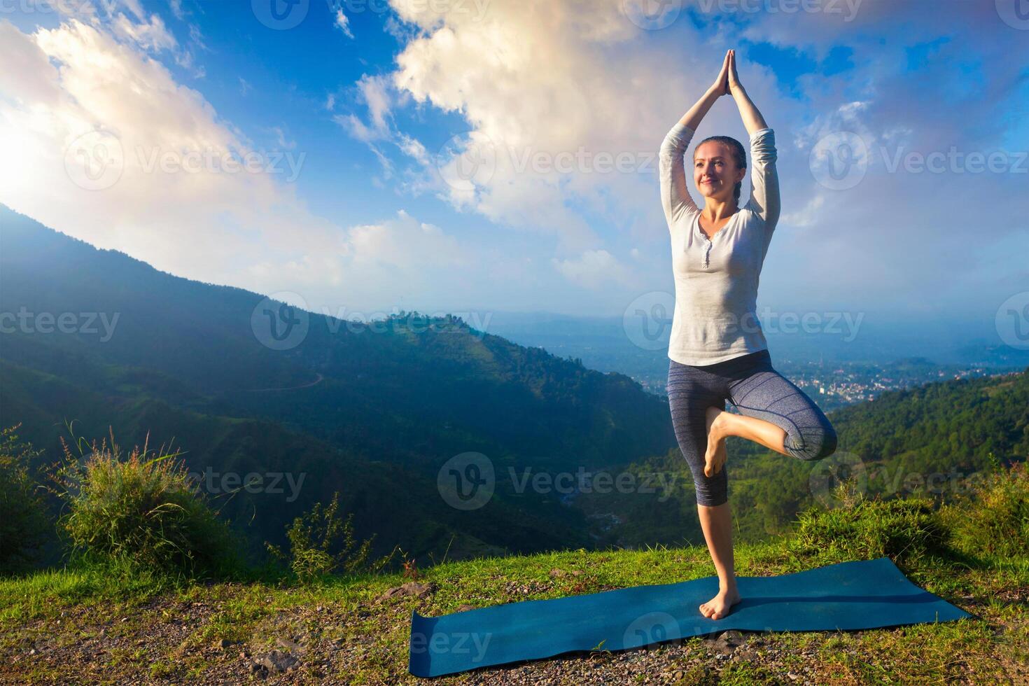 Woman in yoga asana Vrikshasana tree pose in mountains outdoors photo
