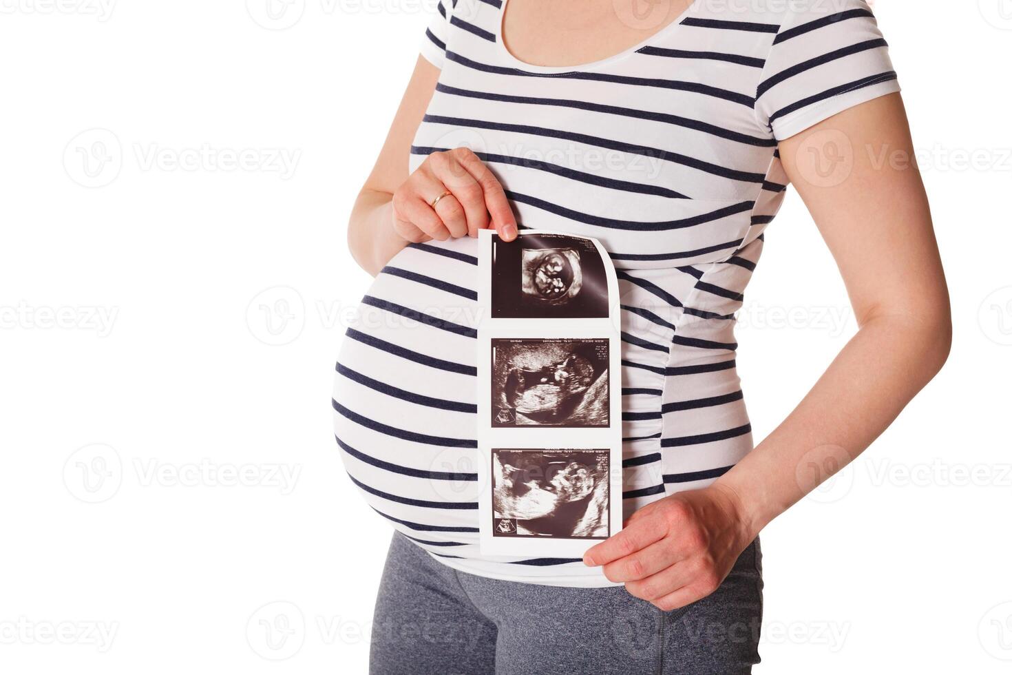 Pregnant woman standing and holding her ultrasound baby scan photo