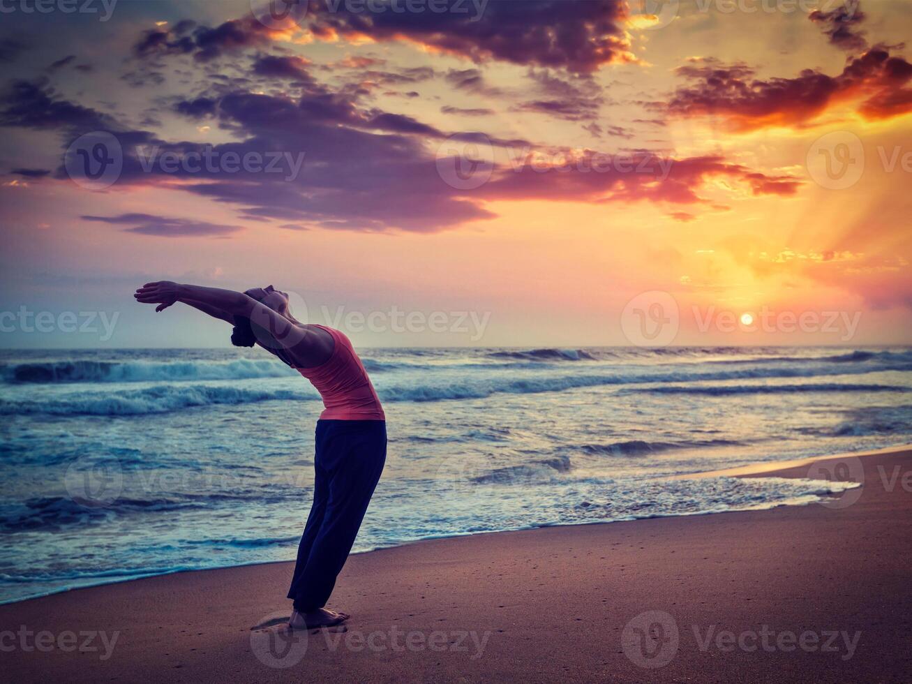 Young sporty fit woman doing yoga Sun salutation Surya Namaskar photo