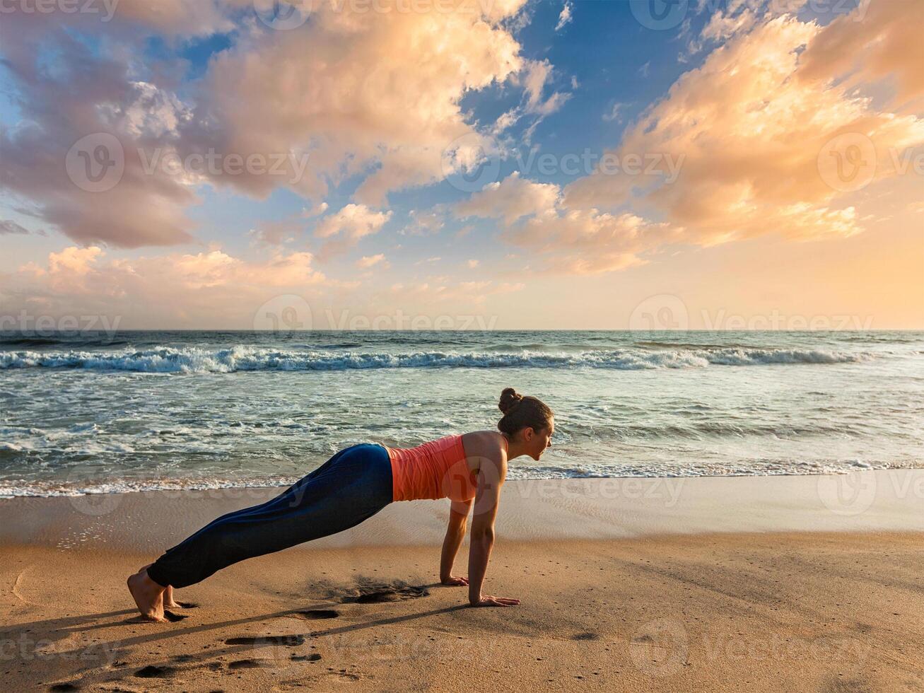 Woman doing Hatha yoga asana plank pose outdoors photo