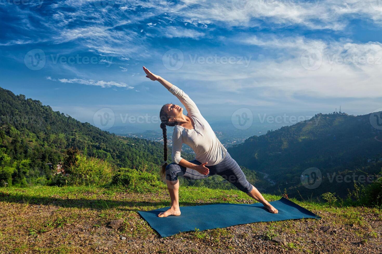 Woman practices yoga asana Utthita Parsvakonasana outdoors photo