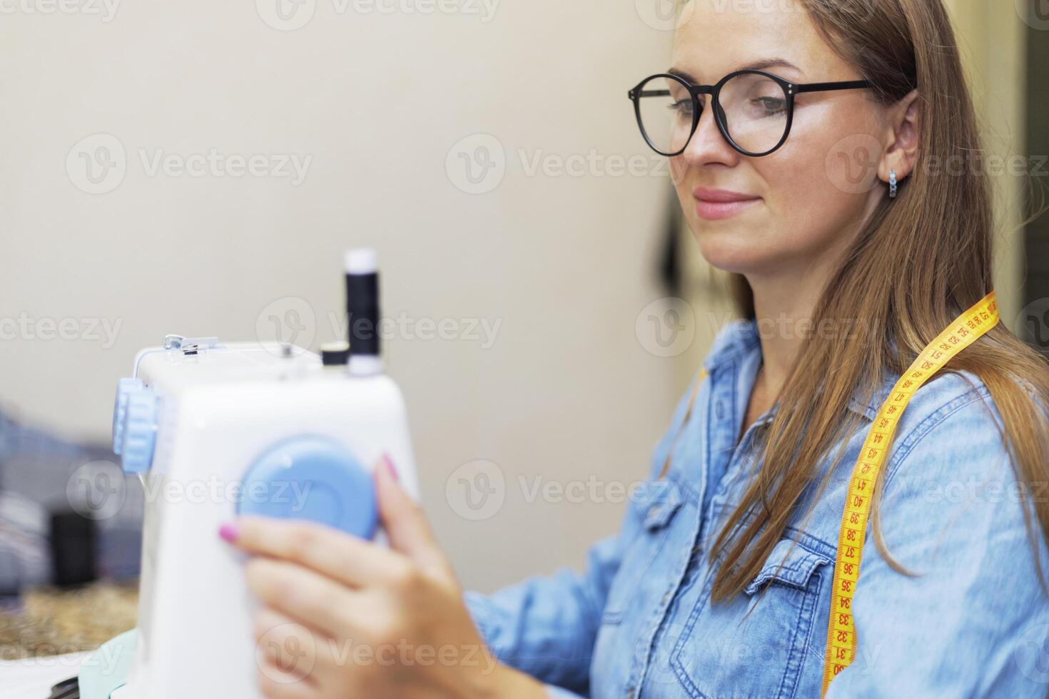 Beautiful young woman sewing clothes using a sewing machine photo