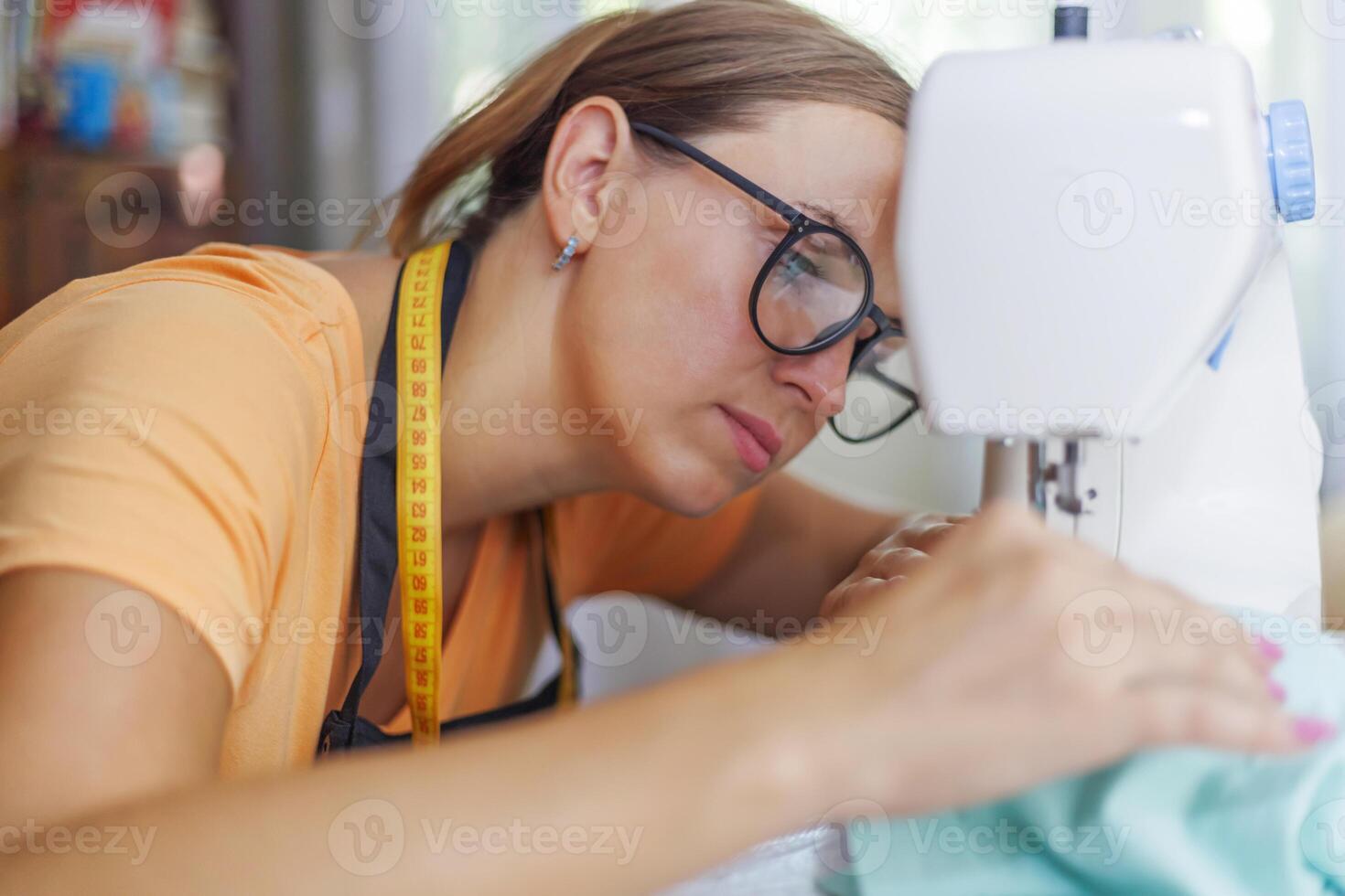 mujer costurera en lentes trabajos en máquina de coser a su lugar de trabajo en taller foto