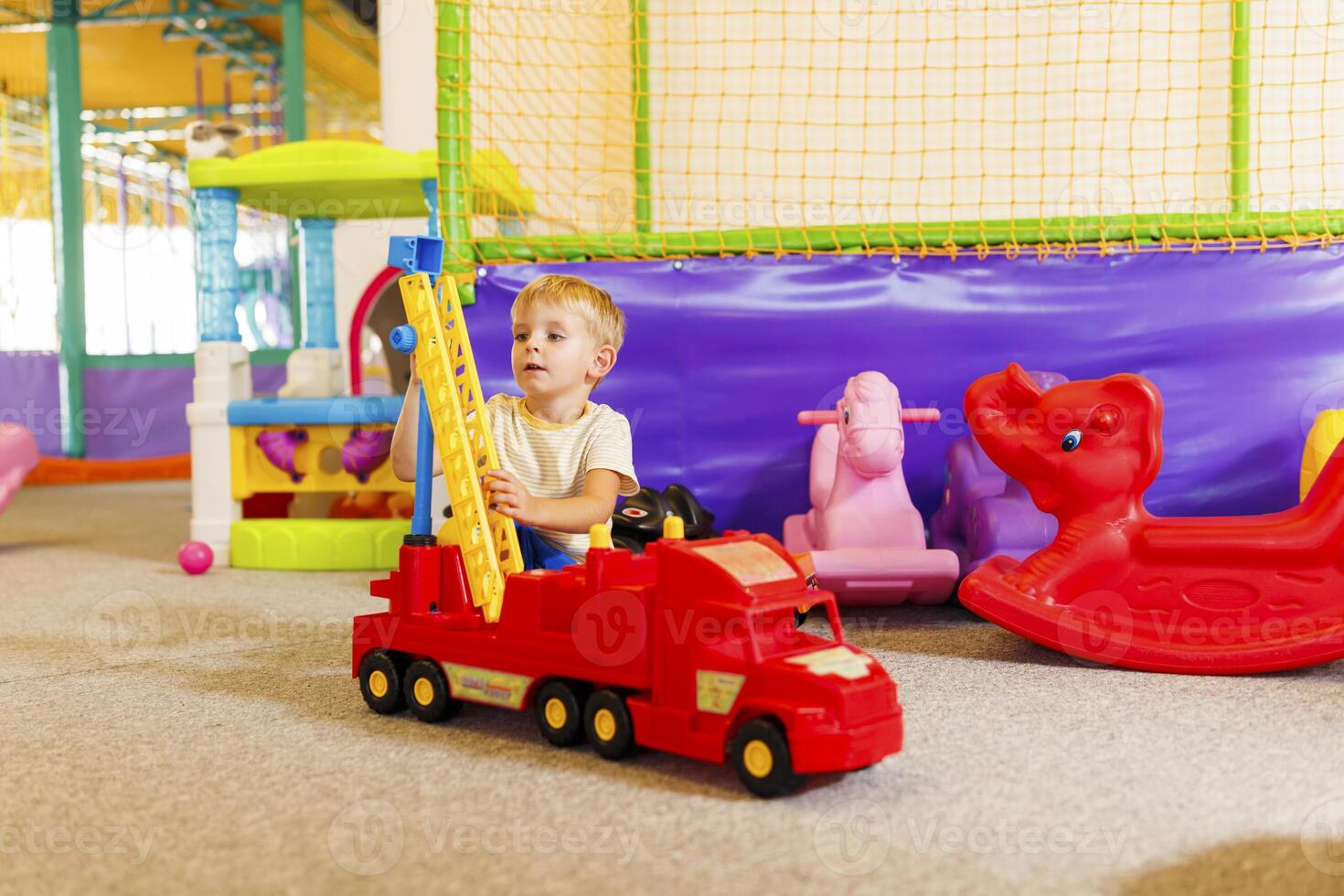 Child Playing with Toy Crane in Playroom photo