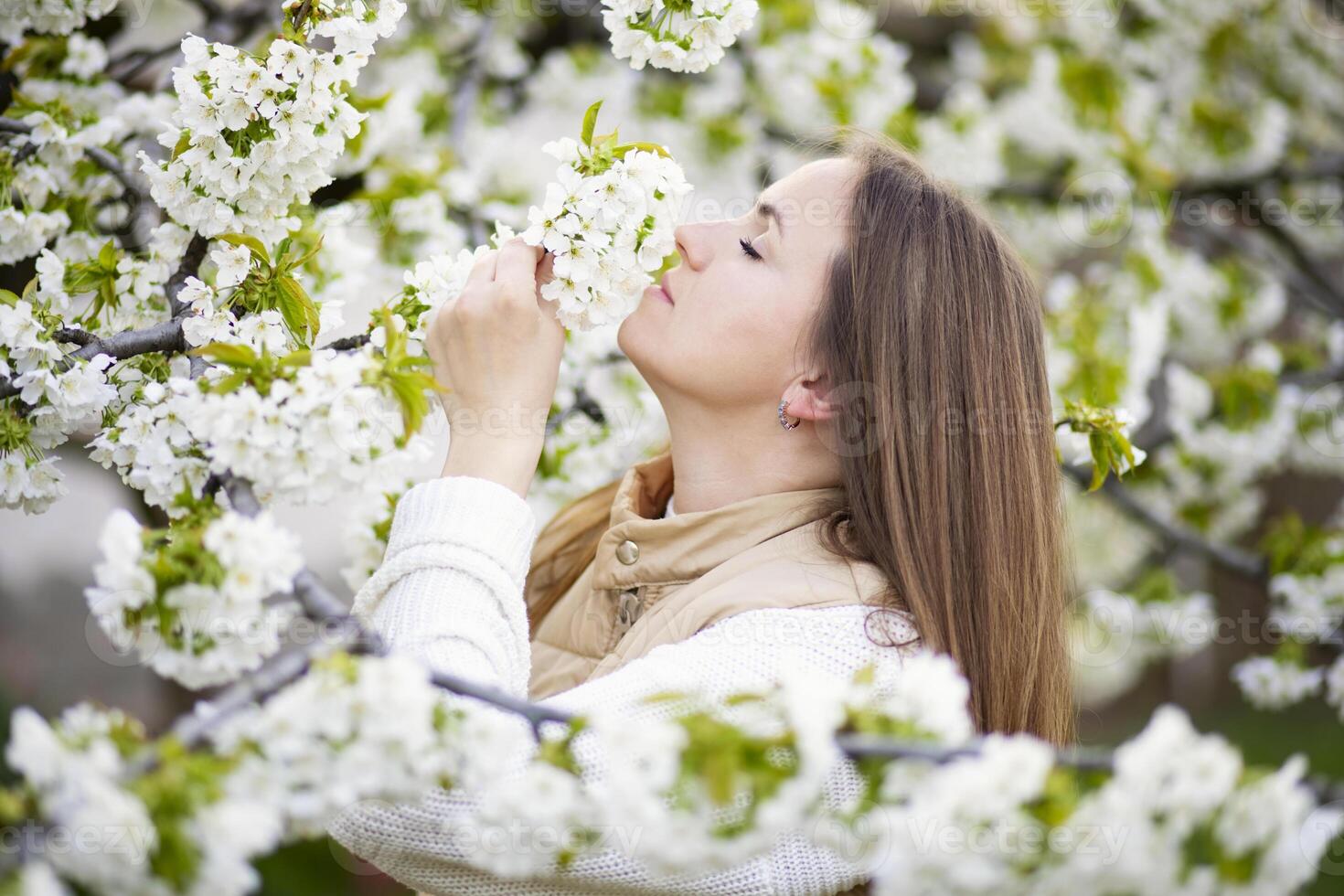 mujer oliendo blanco flores en primavera foto