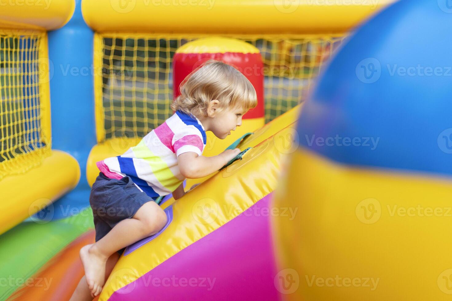 Happy kid having fun on colorful inflatable attraction playground photo