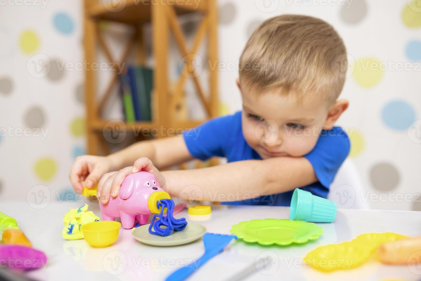 Cute child sitting at the table and plays with playdough photo