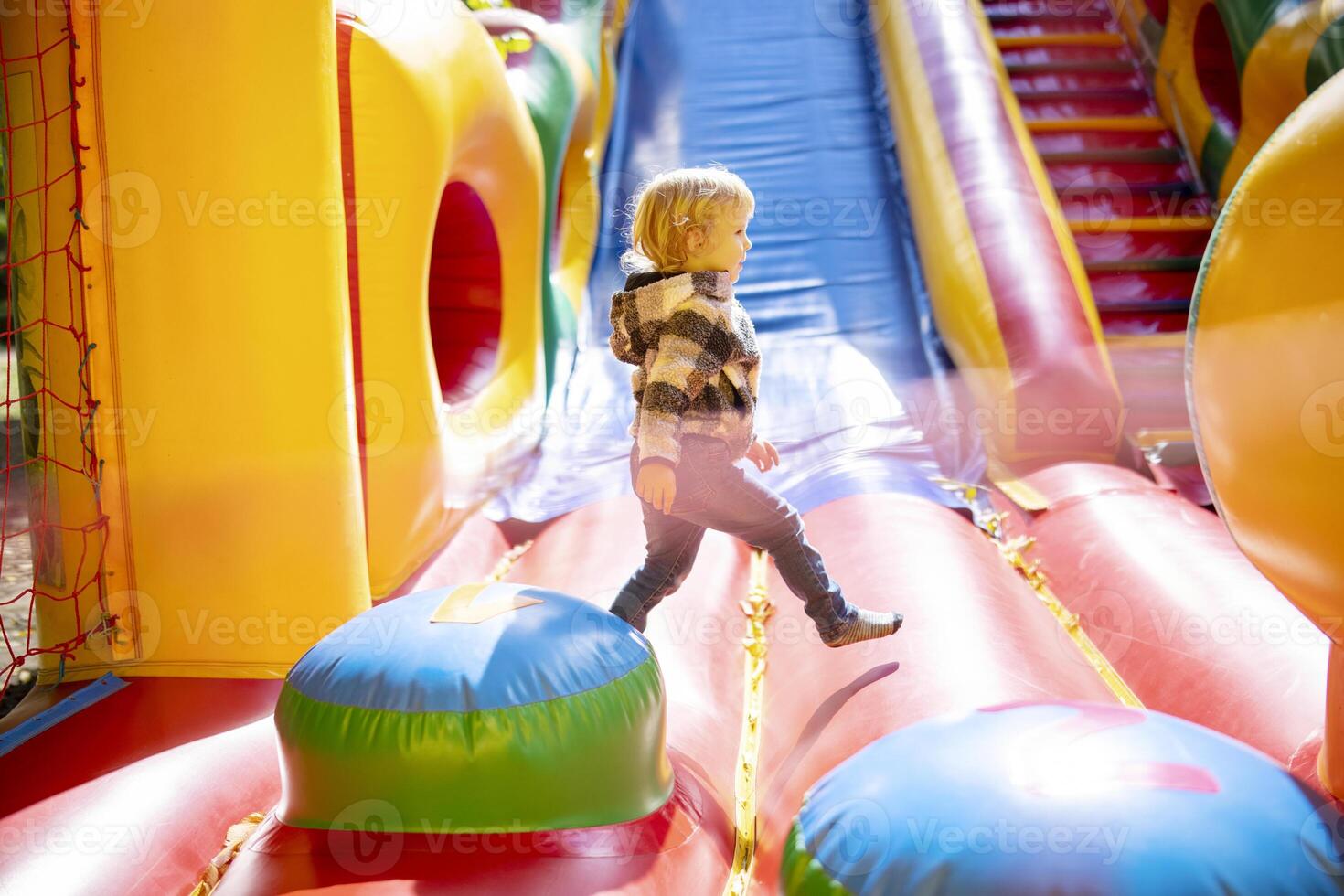 Happy kid having fun on colorful inflatable attraction playground photo