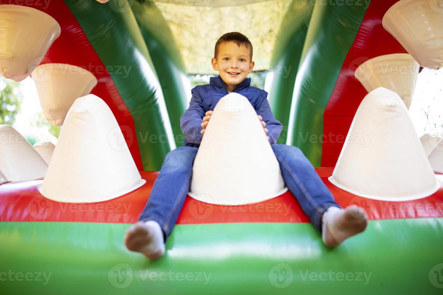 Happy kid having fun on colorful inflatable attraction playground photo