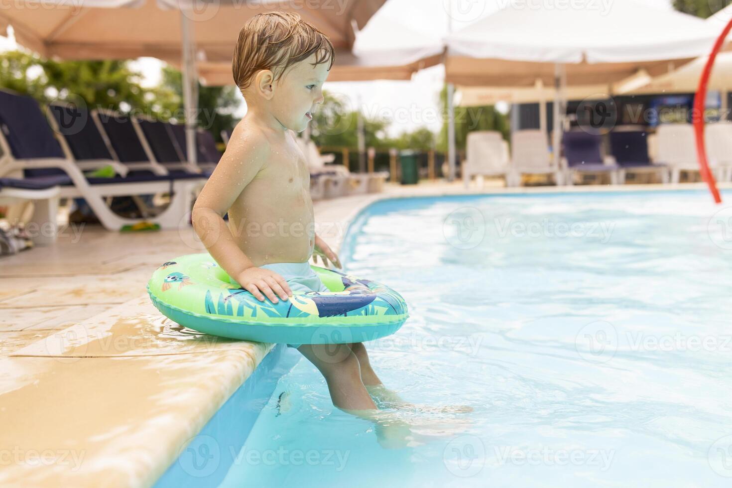 Child in swimming pool with inflatable circle enjoys summer vacation photo