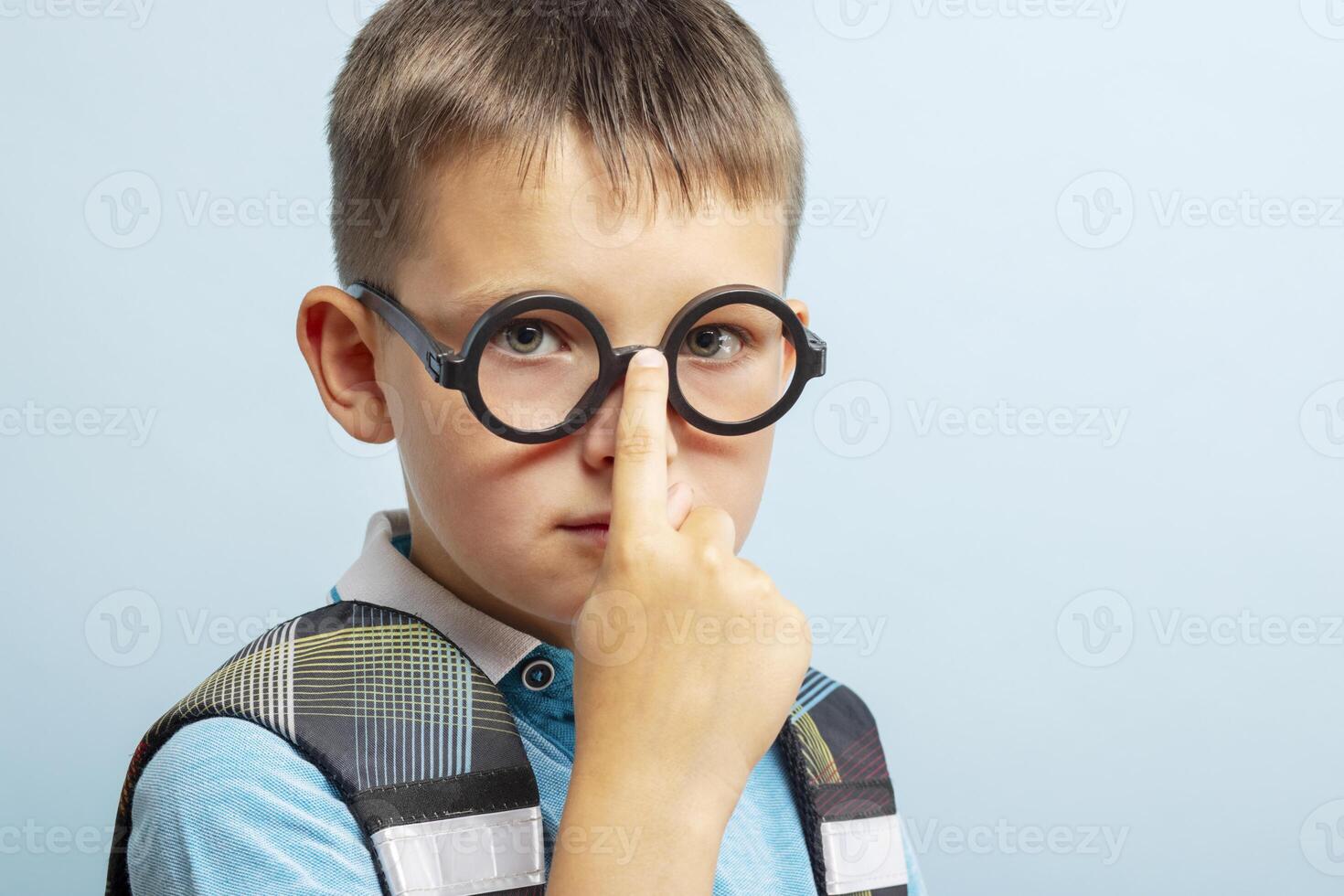 A cute smart school boy in glasses on blue background photo