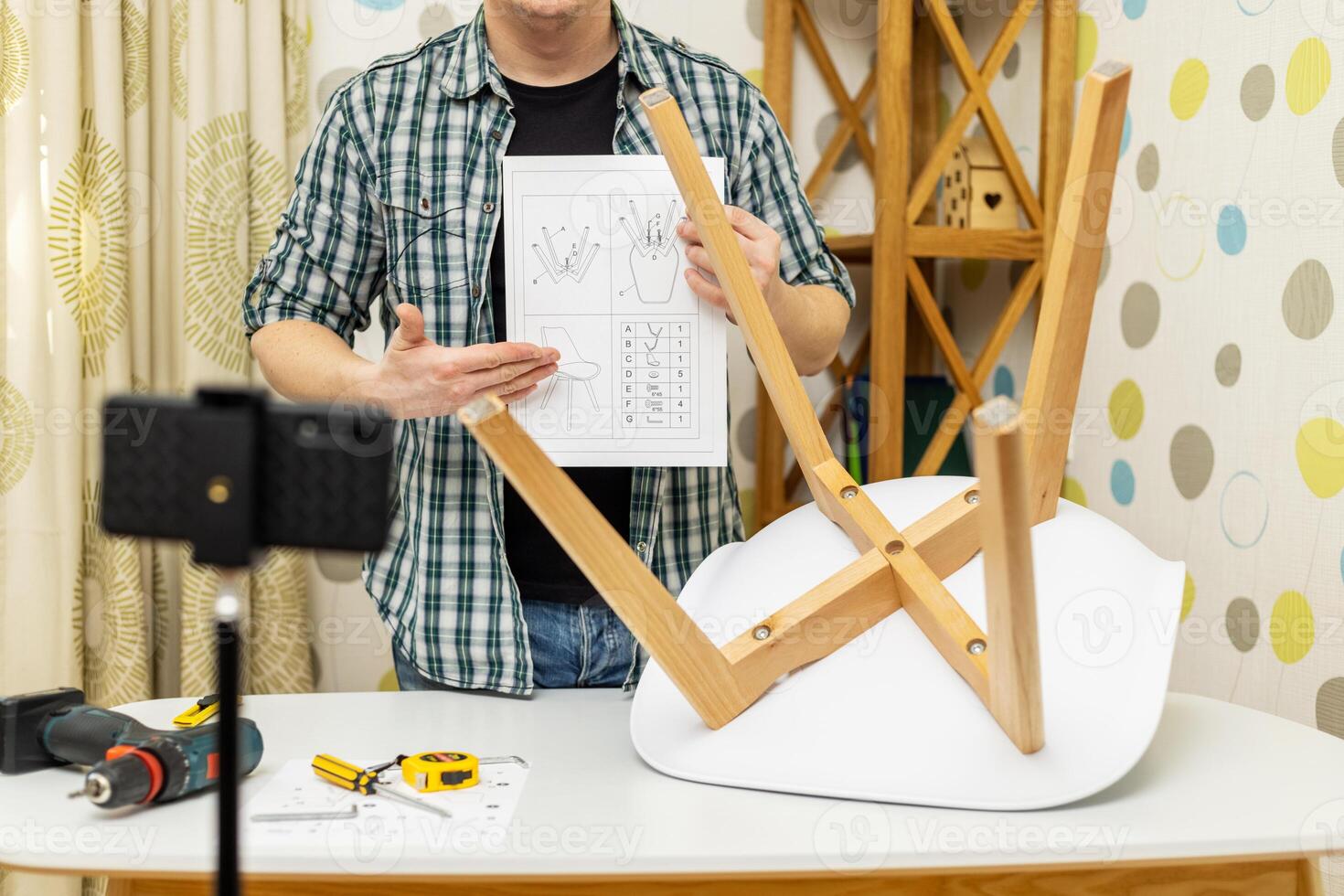 Handyman shows assembling chair, shooting video instructions on smartphone photo