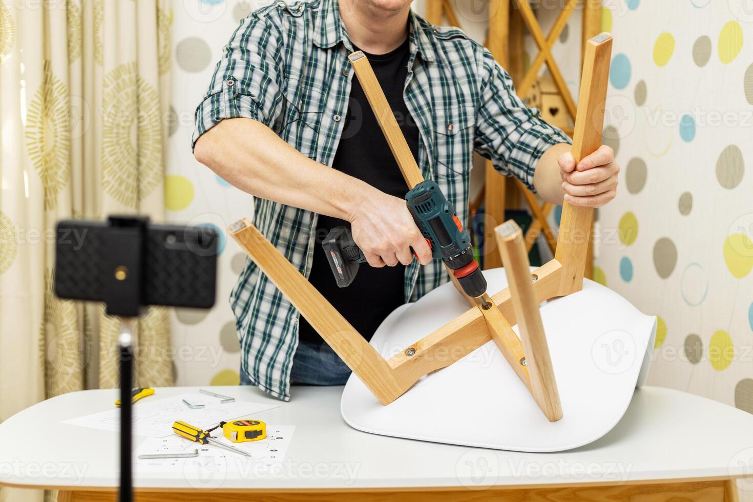 Handyman shows assembling chair, shooting video instructions on smartphone photo