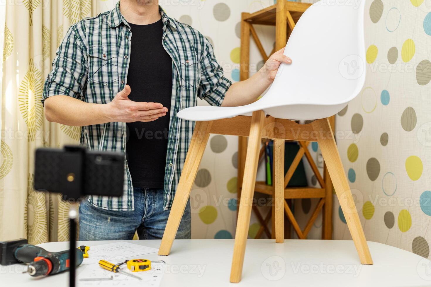Handyman shows assembling chair, shooting video instructions on smartphone photo