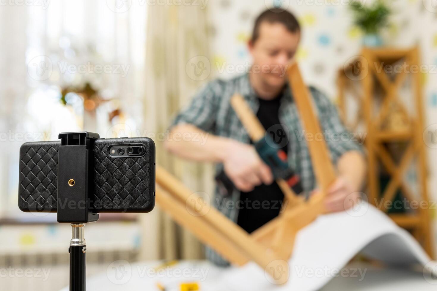 Handyman shows assembling chair, shooting video instructions on smartphone photo