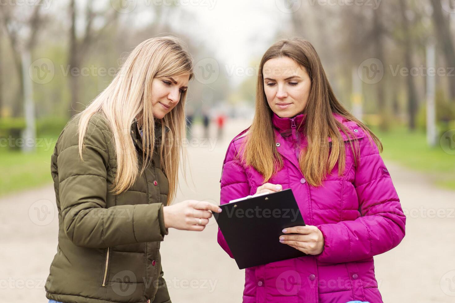 Opinion poll. A woman interviewing people, conducting survey standing outdoor photo