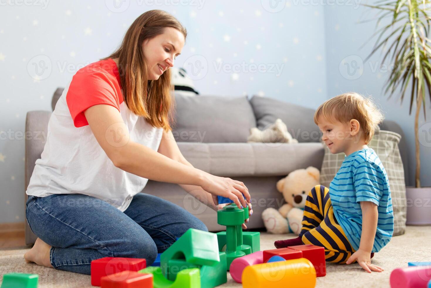 Kid and child development specialist playing together with colorful blocks photo