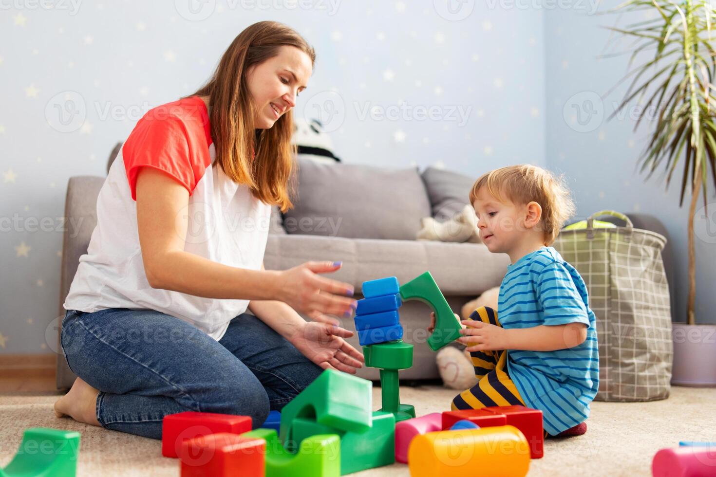 Kid and child development specialist playing together with colorful blocks photo