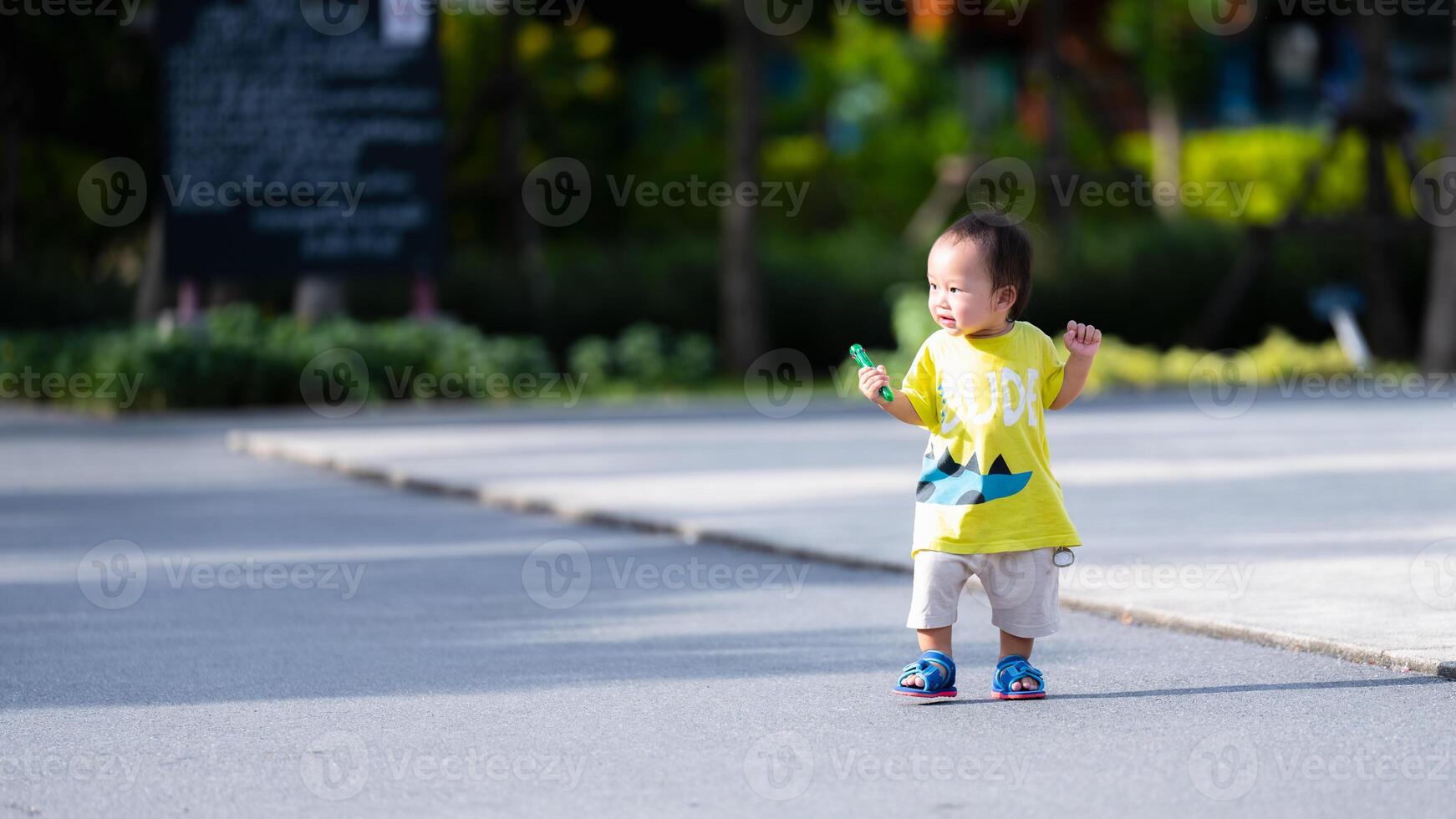 Portrait of a one-year-old Asian boy having fun walking among the playground. In the summer or spring, a child practices walking to develop and strengthen muscles. photo
