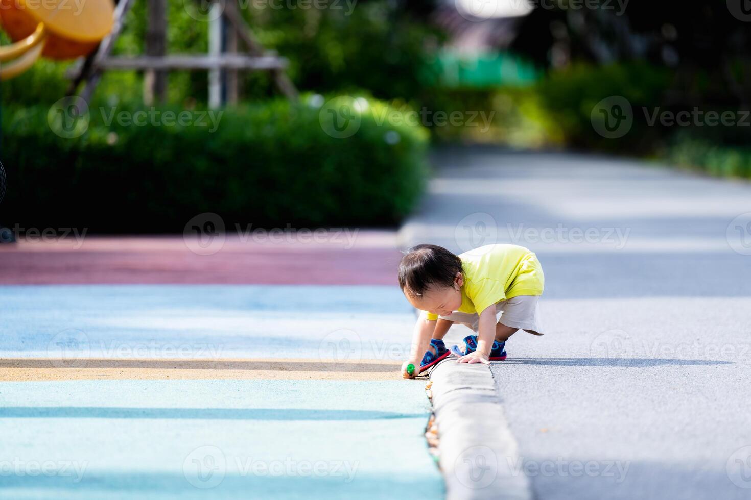 Portrait of Asian baby boy bending over to collect things, level floor, balance body, toddler learning in the world, relaxing time at the park, summer or spring time, one year old child. photo