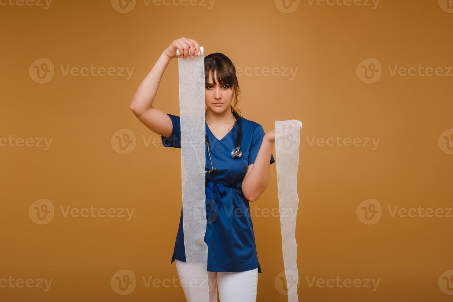 a female doctor in a white coat holds twisted gauze bandages for dressing wounds on a brown background photo