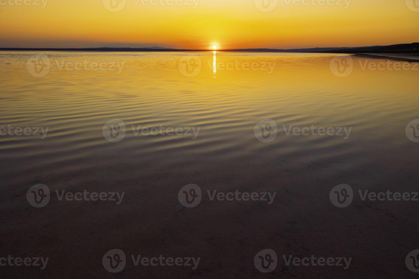 Sunset over the lake. Sunset background photo with calm waves over the lake